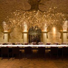 a long table with many place settings under a chandelier hanging from the ceiling