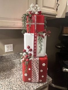 three wrapped presents stacked on top of each other in front of a kitchen countertop