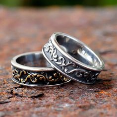 two wedding rings with filigrees on top of each other sitting on a rock