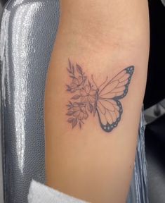 a small butterfly with flowers on it's back side tattooing the arm and shoulder