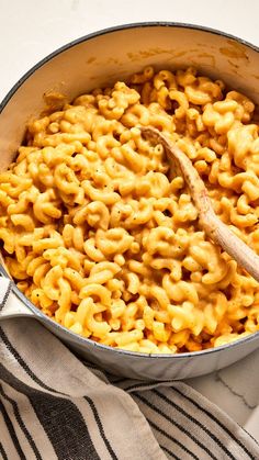 macaroni and cheese is being cooked in a skillet with a wooden spoon