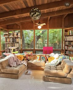 a living room filled with lots of furniture next to a window covered in bookshelves