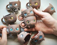 there are many small ceramic cats that have eyes painted on them, and one is holding a coffee cup