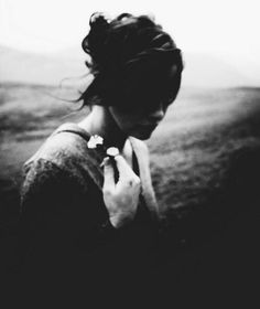 a black and white photo of a woman holding a flower