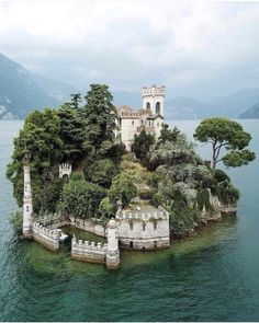 an island in the middle of water with a castle on it's side and trees growing out of it