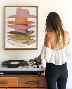 a woman standing next to a record player in front of a painting on the wall