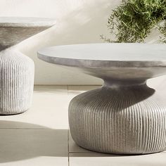 two white vases sitting next to each other on top of a tile floor covered ground