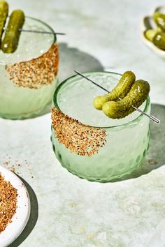 two glasses with pickles in them sitting on a table