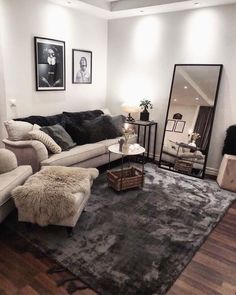 a black and white photo of a living room with couches, rugs and pictures on the wall