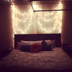 a bed with lights hanging from the ceiling above it and a pillow on top of it