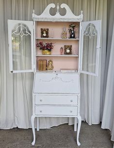 an antique white desk and hutch in front of curtains