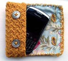 a cell phone in a crocheted case with buttons