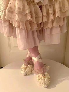 a pair of pink ballet shoes sitting on top of a white table next to a curtain