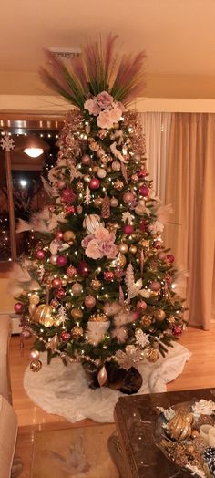 a christmas tree decorated with pink and gold ornaments in a living room area next to a window