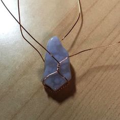 a piece of wire wrapped around a blue stone on top of a wooden table next to wires