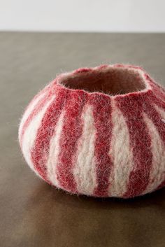 a red and white striped vase sitting on top of a table