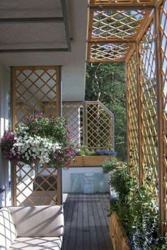 a wooden porch with flowers and trelliss on the wall, next to a bench