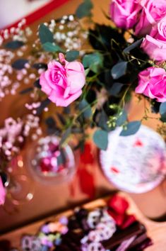 pink roses in a vase on a table next to chocolates and other food items