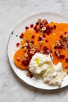 a white plate topped with sliced up oranges and whipped cream covered in pomegranate