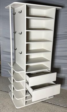 an empty white cabinet with drawers on the top and bottom shelves in front of it