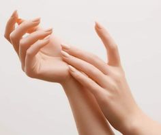 a woman's hands with manicured nails holding an orange object