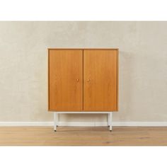 a wooden cabinet sitting on top of a hard wood floor next to a white wall