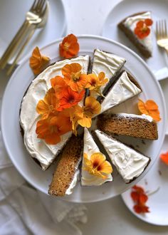 a white plate topped with a cake covered in frosting and orange pansies on top of it