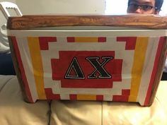 a man sitting on a couch holding a large wooden box with letters painted on it