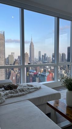 a living room filled with furniture and large windows overlooking the cityscape in new york