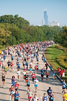 a large group of people are running down the street in a marathon with skyscrapers in the background