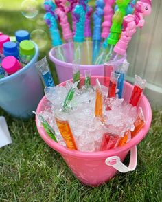 there are many different colored toothbrushes in the buckets on the grass outside