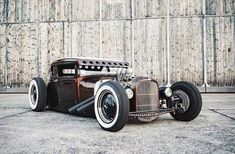 an old fashioned car parked in front of a wooden wall