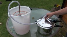 a person pouring water into a bucket on top of a glass table with a hose attached to it