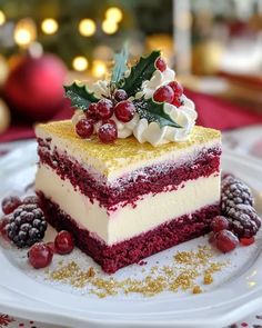 a piece of red velvet cake on a white plate with holly and berries around it