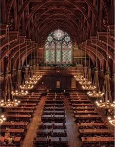 the interior of a large cathedral with stained glass windows and wooden pews on both sides