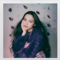 a woman with long black hair is posing in front of butterflies