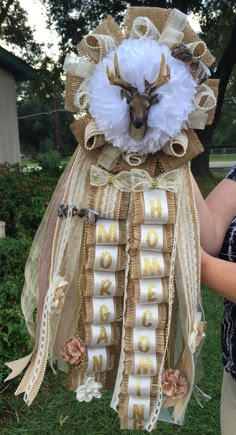 a woman holding up a stuffed animal made out of ribbon and ribbons with the word mom written on it