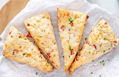 four pieces of pizza sitting on top of a piece of wax paper with sprinkles