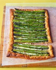 a pizza with asparagus on it sitting on top of a cutting board