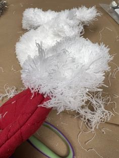 a red and white stuffed animal sitting on top of a table next to some scissors