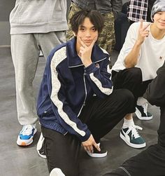 several young men sitting on the ground with one pointing at his face and another standing behind him