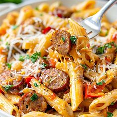 a pasta dish with sausage, tomatoes and parmesan cheese in a white bowl