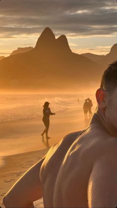 the man is walking on the beach with his back to the camera as people walk in the background