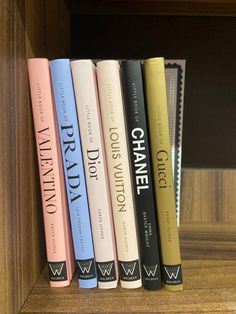 four books sitting on top of a wooden shelf next to each other in front of a bookcase