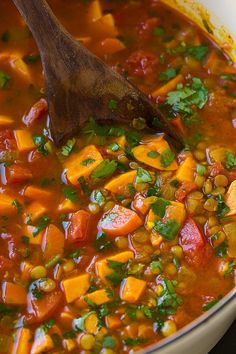 a wooden spoon in a pot filled with vegetable soup