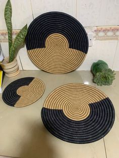 three black and tan placemats sitting on a counter next to a potted plant