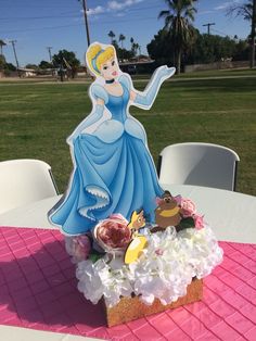 a table topped with a cake covered in frosting and princess figurines on top of it