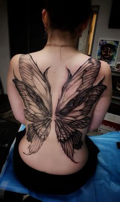 the back of a woman's body with black and grey wings on her back