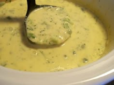 a ladle in a white crock pot filled with broccoli cheese soup