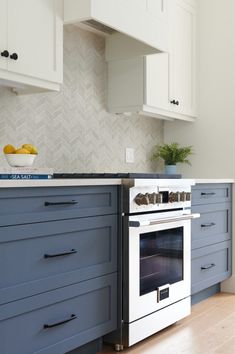 a white stove top oven sitting inside of a kitchen next to blue cabinets and drawers